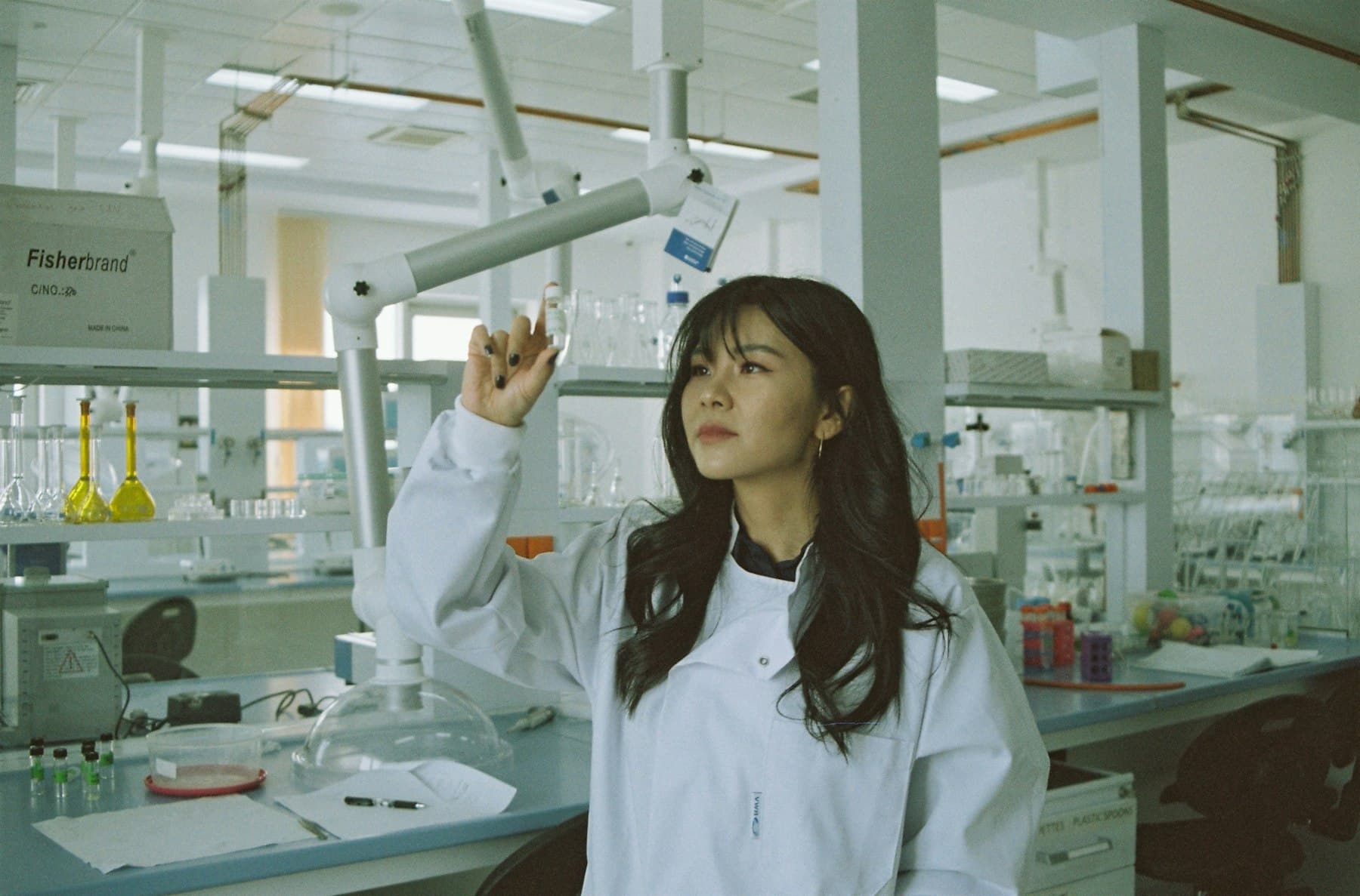 A researcher in a laboratory holding a sample vial up to the light.